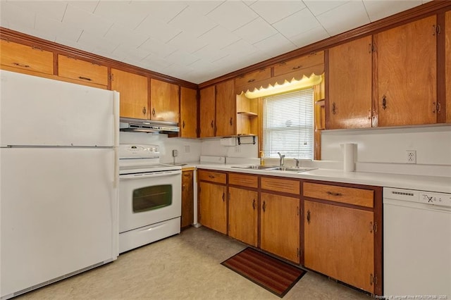 kitchen with white appliances, under cabinet range hood, brown cabinets, and a sink