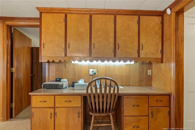 kitchen with brown cabinetry, light countertops, and built in study area