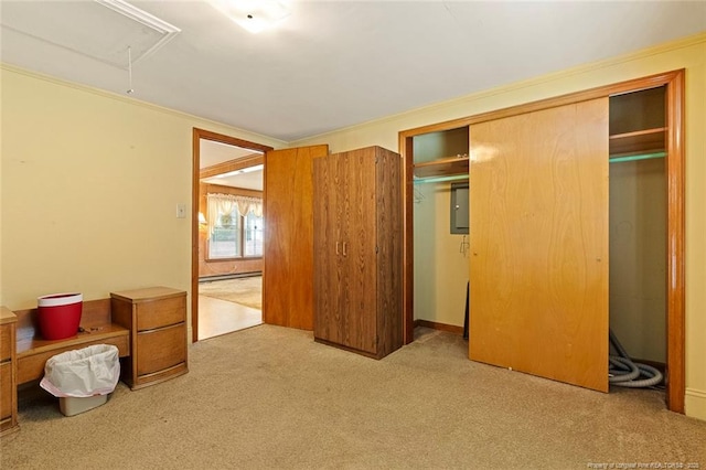 unfurnished bedroom with carpet, crown molding, a closet, baseboard heating, and attic access