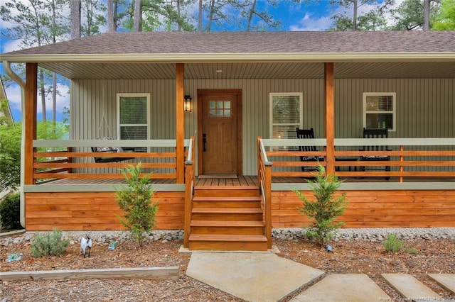 entrance to property featuring a porch and a shingled roof