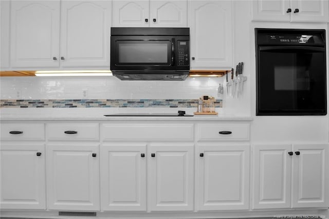 kitchen with visible vents, light countertops, backsplash, white cabinetry, and black appliances