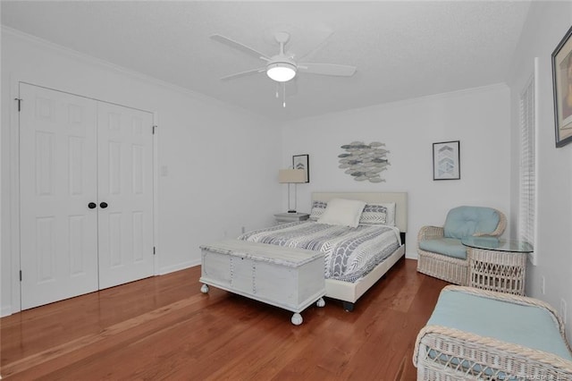 bedroom with ceiling fan, a closet, ornamental molding, and wood finished floors