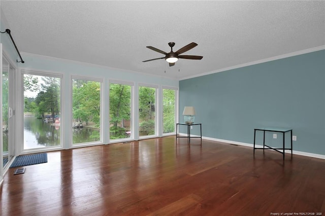 empty room with a textured ceiling, ceiling fan, wood finished floors, and crown molding