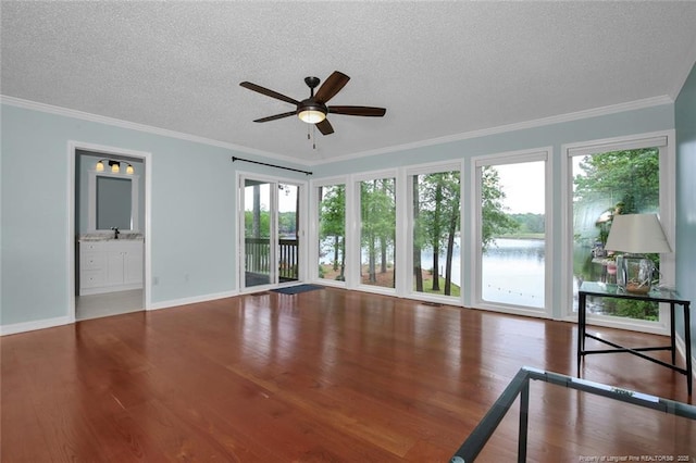 unfurnished living room featuring a textured ceiling, ornamental molding, a water view, and wood finished floors