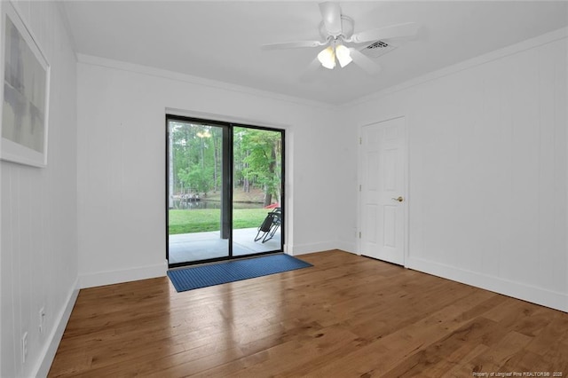 empty room with a ceiling fan, wood finished floors, visible vents, and crown molding