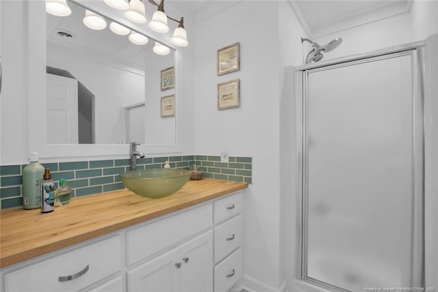 bathroom featuring a stall shower, vanity, visible vents, and decorative backsplash