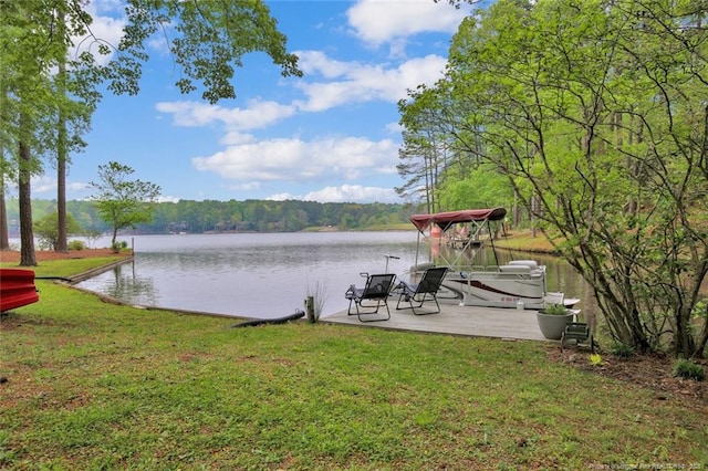 dock area with a water view, a yard, and a view of trees