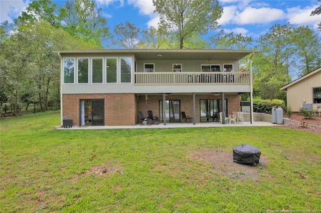 rear view of house featuring a yard, brick siding, and a patio area