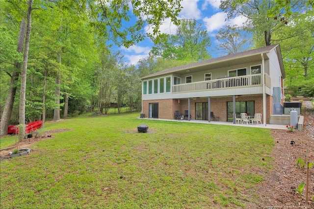 rear view of house with brick siding, a patio, and a lawn