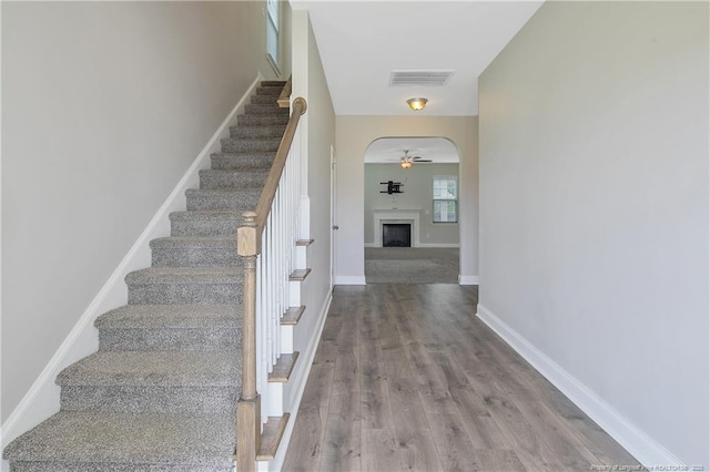 387 Springhaven Dr, Raeford, NC 28376 - stairway featuring a ceiling fan, wood finished floors, a fireplace, baseboards, and arched walkways