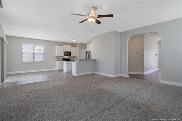 387 Springhaven Dr, Raeford, NC 28376 - unfurnished living room featuring arched walkways, a ceiling fan, carpet floors, baseboards, and a chandelier