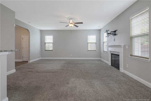 387 Springhaven Dr, Raeford, NC 28376 - unfurnished living room with ceiling fan, carpet floors, a fireplace, arched walkways, and baseboards