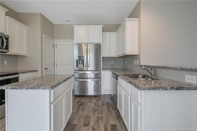 387 Springhaven Dr, Raeford, NC 28376 - kitchen featuring stainless steel appliances, a sink, backsplash, stone counters, and light wood-style flooring