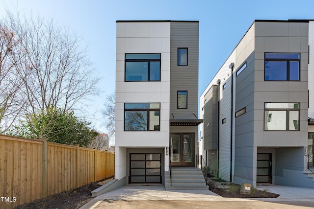 contemporary house featuring driveway, french doors, and fence