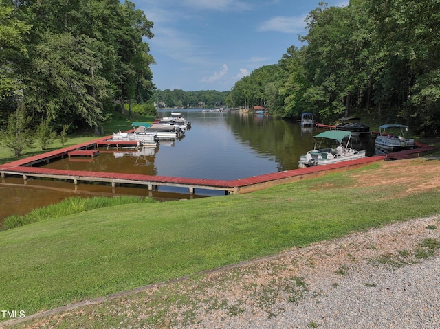 dock area featuring a yard, a view of trees, and a water view