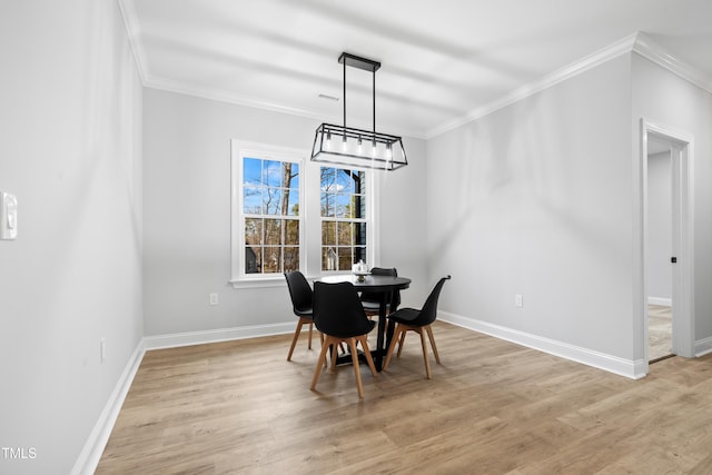 dining room with light wood-type flooring, baseboards, visible vents, and ornamental molding