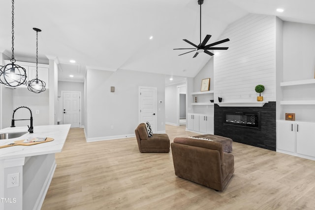 living room featuring built in shelves, a fireplace, light wood-style floors, and baseboards