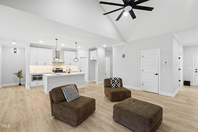 living room featuring a ceiling fan, baseboards, high vaulted ceiling, light wood-style floors, and crown molding