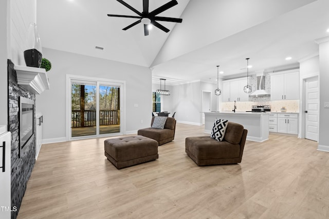 living room with visible vents, light wood-style flooring, a fireplace, and ceiling fan with notable chandelier