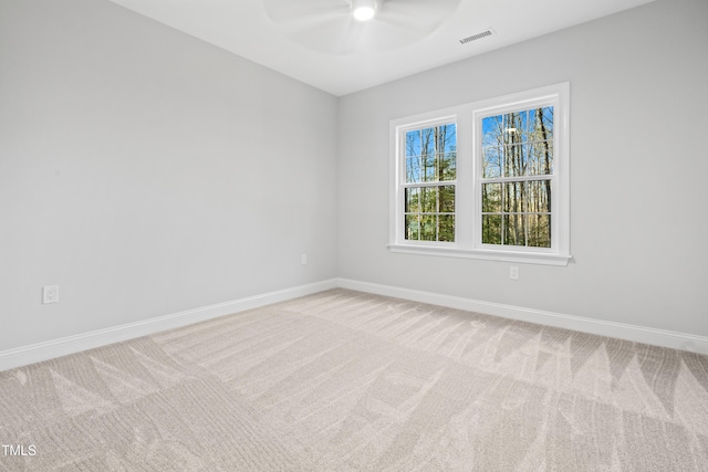 carpeted spare room featuring visible vents, a ceiling fan, and baseboards