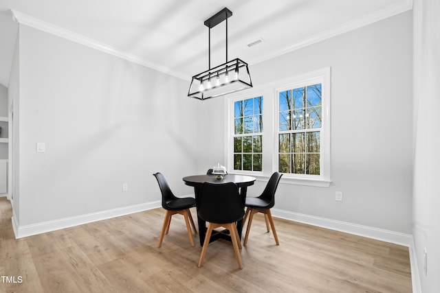 dining area featuring visible vents, baseboards, light wood-style floors, and crown molding