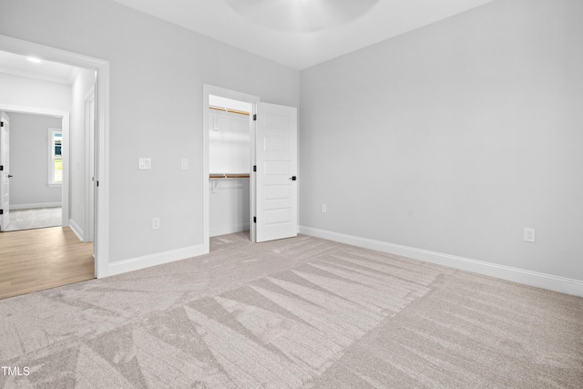 unfurnished bedroom with a closet, baseboards, a spacious closet, and carpet flooring