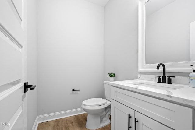 bathroom featuring vanity, toilet, wood finished floors, and baseboards