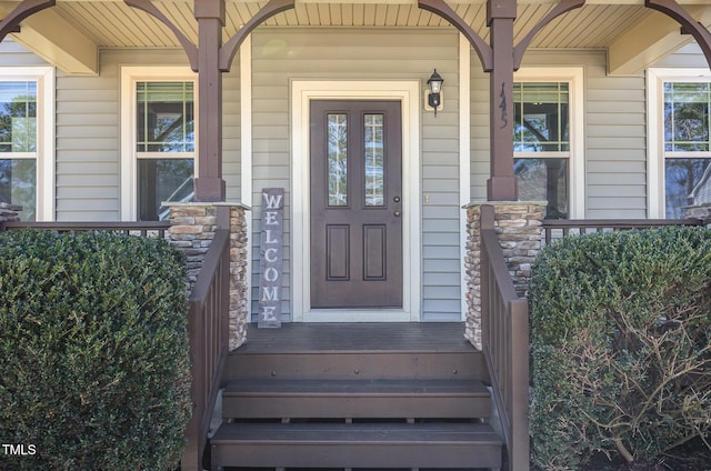 view of exterior entry featuring stone siding and covered porch