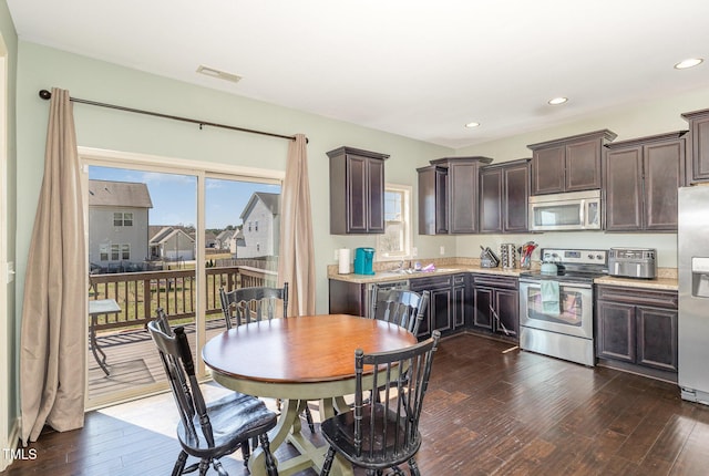 kitchen with stainless steel appliances, dark brown cabinets, dark wood-style flooring, and light countertops