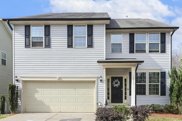 traditional home featuring an attached garage, a shingled roof, and driveway