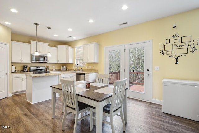 dining space with dark wood-style flooring, visible vents, and a wealth of natural light