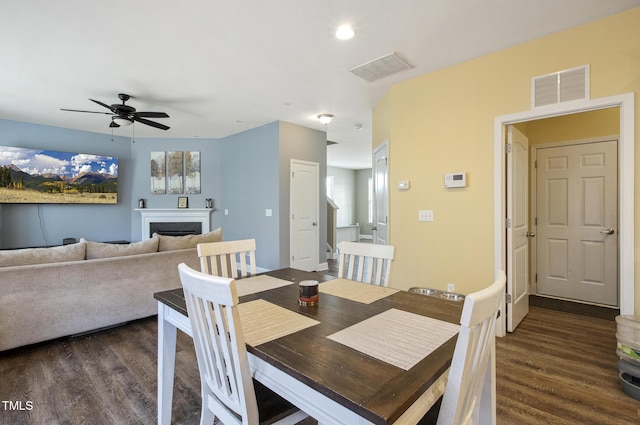 dining area featuring ceiling fan, visible vents, dark wood-style floors, and a fireplace