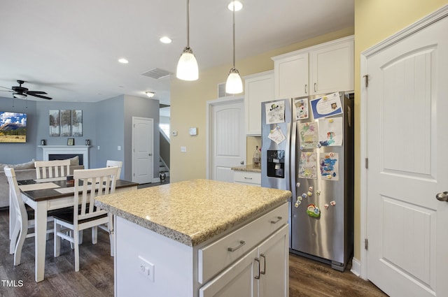 kitchen featuring visible vents, ceiling fan, dark wood-type flooring, stainless steel refrigerator with ice dispenser, and a center island