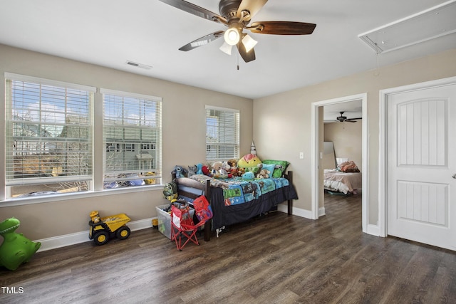 bedroom with visible vents, attic access, baseboards, and wood finished floors