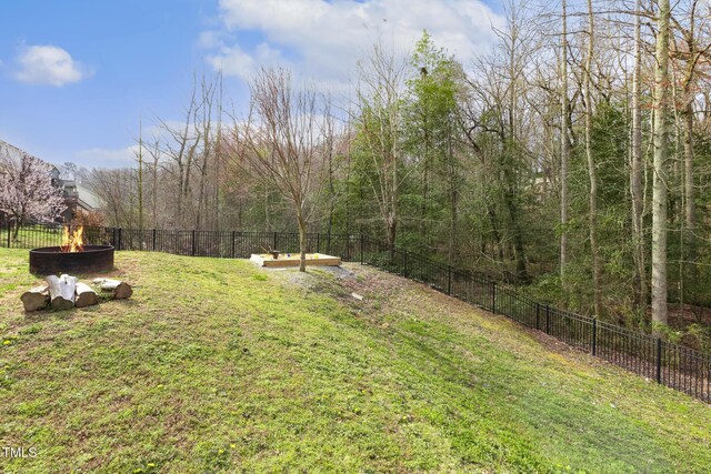 view of yard featuring a garden, a fire pit, and fence