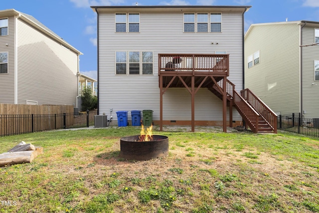 back of house featuring stairway, a wooden deck, a fire pit, crawl space, and a lawn