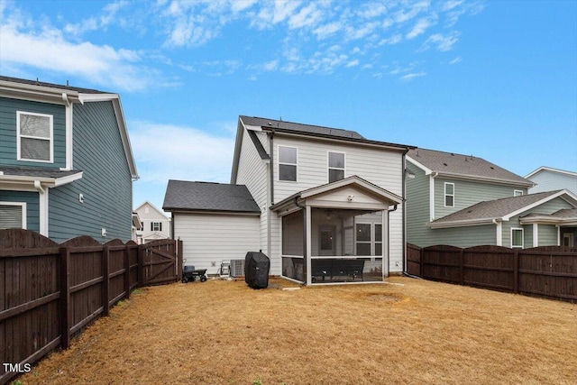 rear view of property with a yard, cooling unit, a fenced backyard, and a sunroom