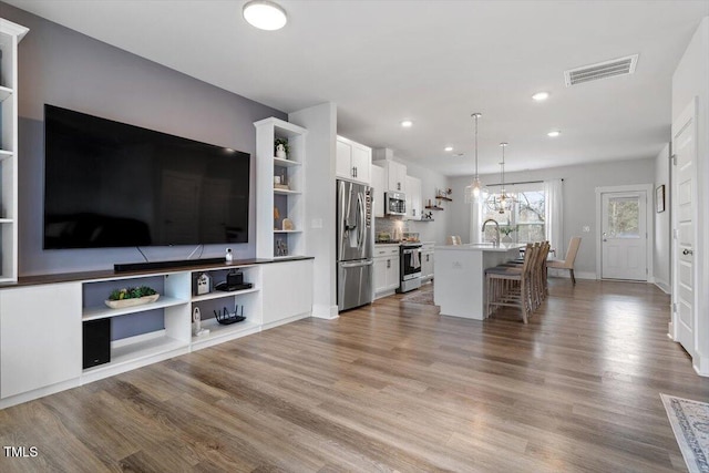 living room featuring recessed lighting, visible vents, baseboards, and wood finished floors