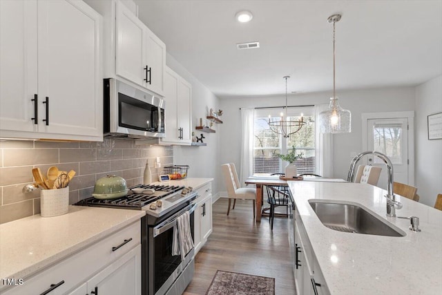 kitchen with visible vents, a sink, stainless steel appliances, white cabinets, and tasteful backsplash