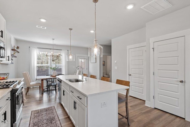 kitchen with visible vents, a sink, a kitchen breakfast bar, gas range oven, and white cabinetry