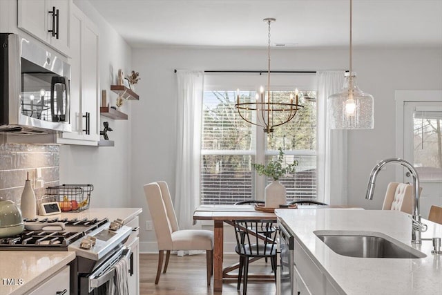 kitchen featuring a sink, stainless steel appliances, decorative backsplash, and white cabinetry