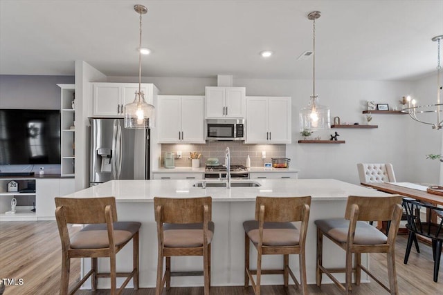 kitchen featuring tasteful backsplash, open shelves, stainless steel appliances, white cabinetry, and a sink