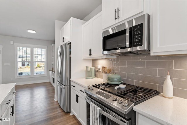 kitchen featuring decorative backsplash, appliances with stainless steel finishes, wood finished floors, and white cabinetry