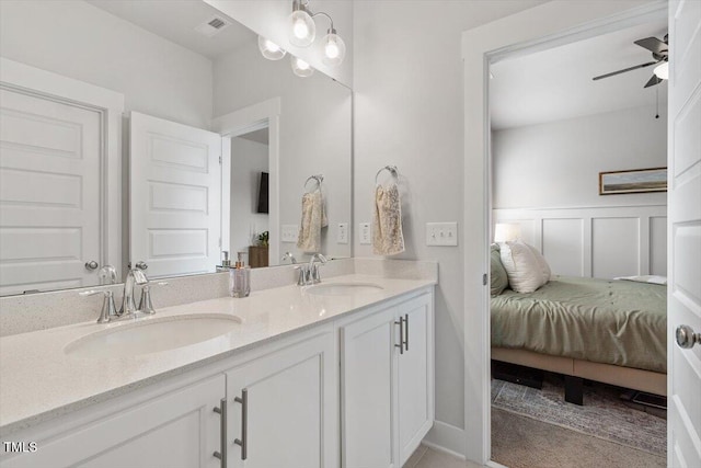 bathroom with double vanity, a decorative wall, visible vents, and a sink