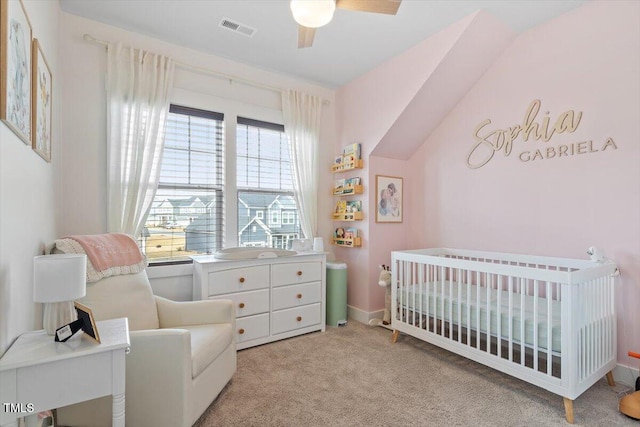 carpeted bedroom featuring visible vents, a crib, and ceiling fan