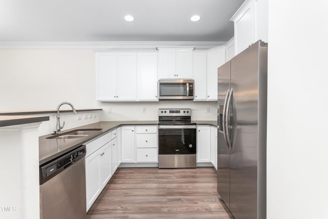 kitchen featuring dark countertops, ornamental molding, appliances with stainless steel finishes, and a sink