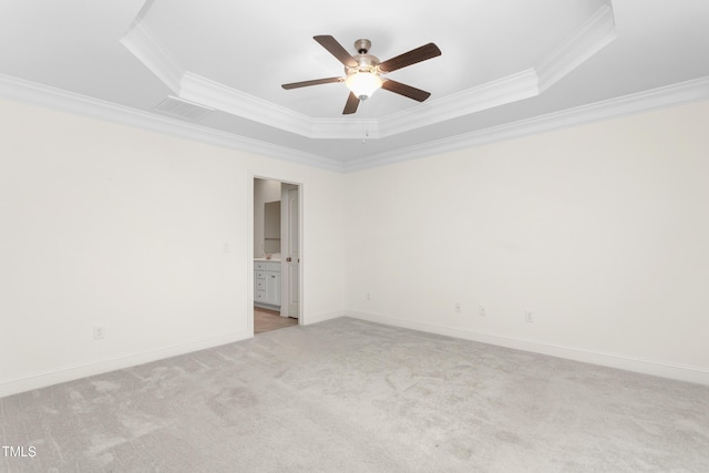 spare room featuring ceiling fan, baseboards, a tray ceiling, ornamental molding, and light carpet