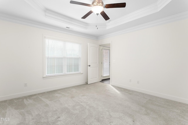 carpeted spare room with a tray ceiling, baseboards, and ornamental molding