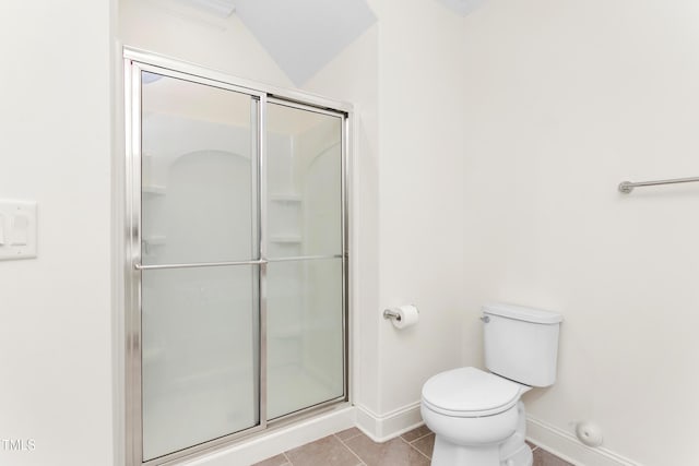 bathroom featuring tile patterned flooring, a stall shower, toilet, and baseboards