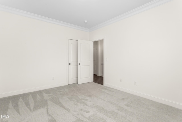 carpeted empty room with crown molding and baseboards